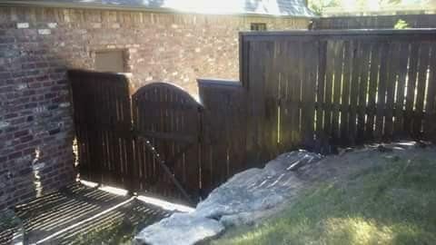A wooden fence is surrounded by rocks and a brick wall.
