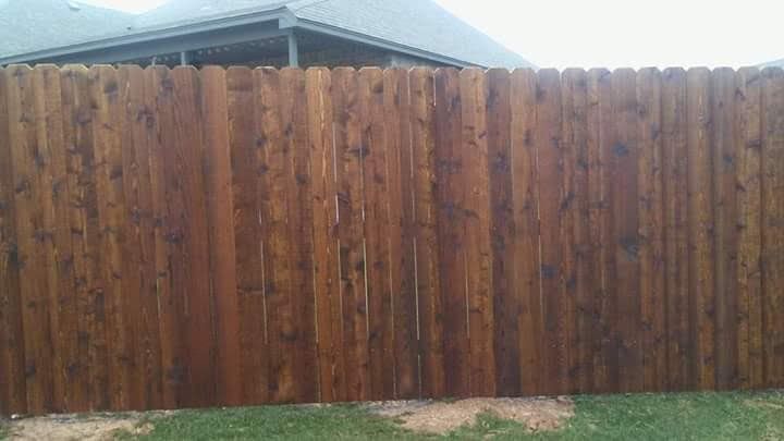 A wooden fence is sitting in the grass in front of a house.
