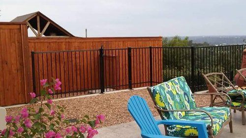 A patio with chairs and a fence with a view of the ocean.