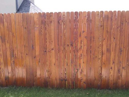 A wooden fence is sitting in the grass in front of a house.
