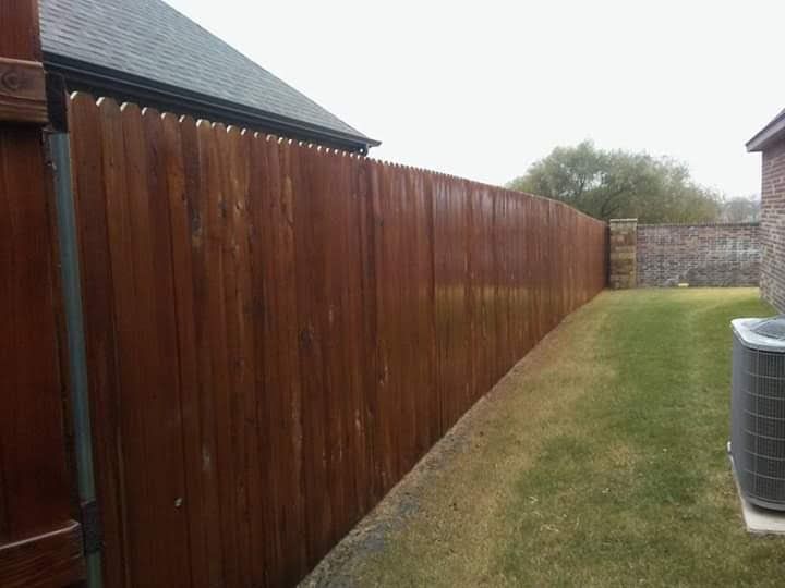A wooden fence is in the backyard of a house.