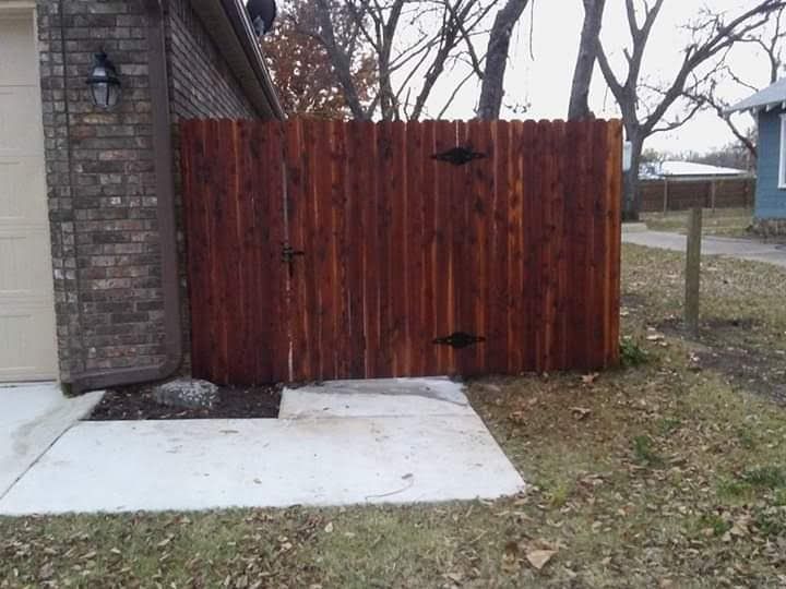 A wooden fence is in front of a brick house