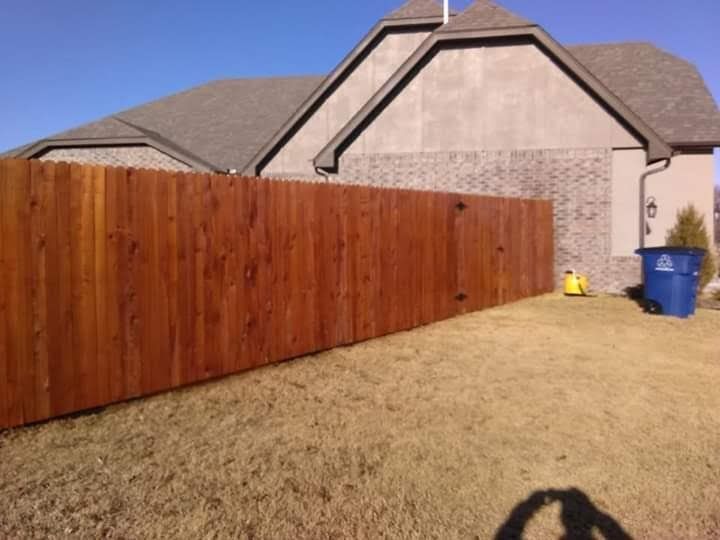 A wooden fence is in front of a house.