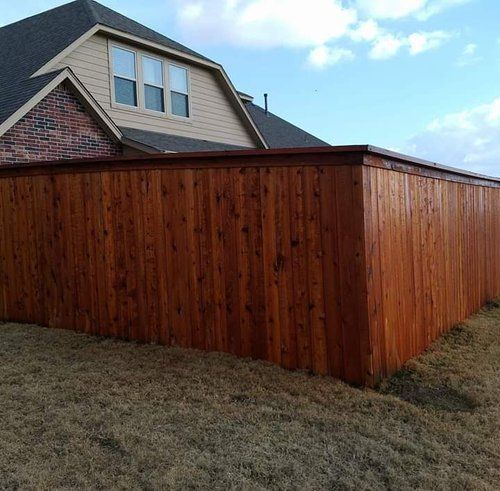 A wooden fence is in front of a house.