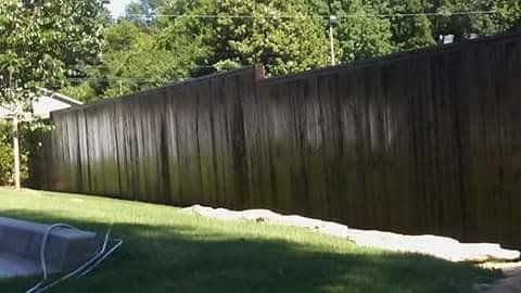 A large wooden fence is sitting in the middle of a lush green yard.