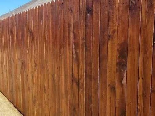 A close up of a wooden fence with a blue sky in the background.