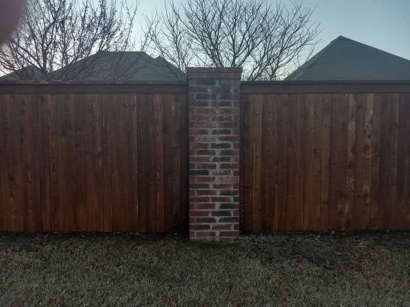 A wooden fence with a brick post in the middle of it.