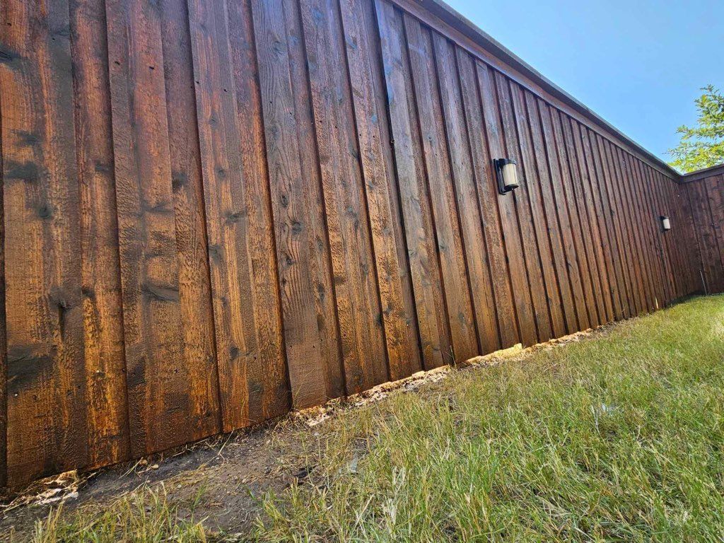 A wooden fence is sitting on top of a lush green field.