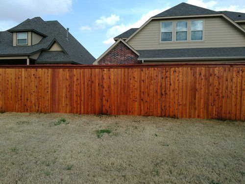 A wooden fence in front of a house with a gray roof