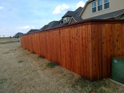 A wooden fence is in the backyard of a house.
