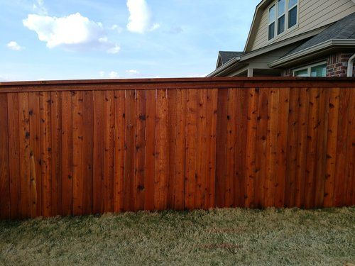 A wooden fence is in the backyard of a house.