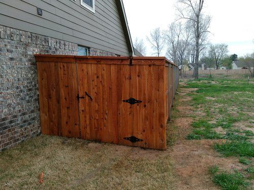 A wooden fence is sitting next to a brick house.