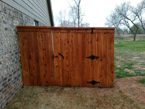 A wooden fence is sitting on the side of a brick building.
