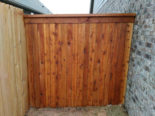 A wooden fence is sitting next to a brick wall.