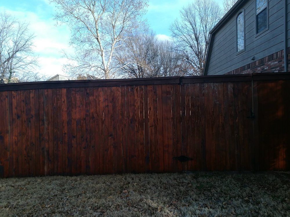 A wooden fence is in the backyard of a house.