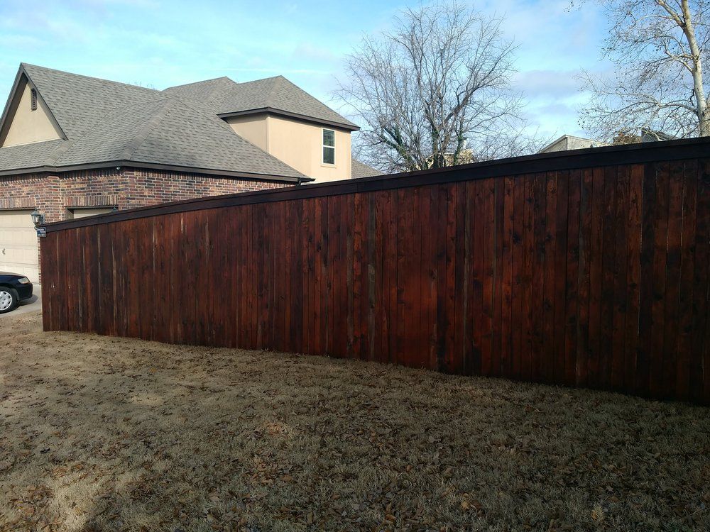 A wooden fence is in the backyard of a house.