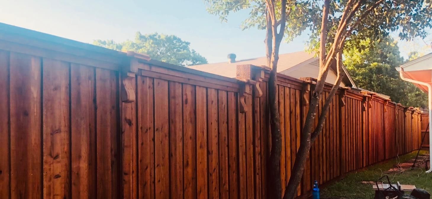 A wooden fence with a tree in the backyard of a house.