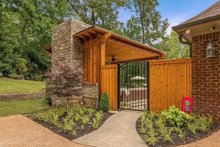 A brick house with a wooden fence and a walkway leading to it.