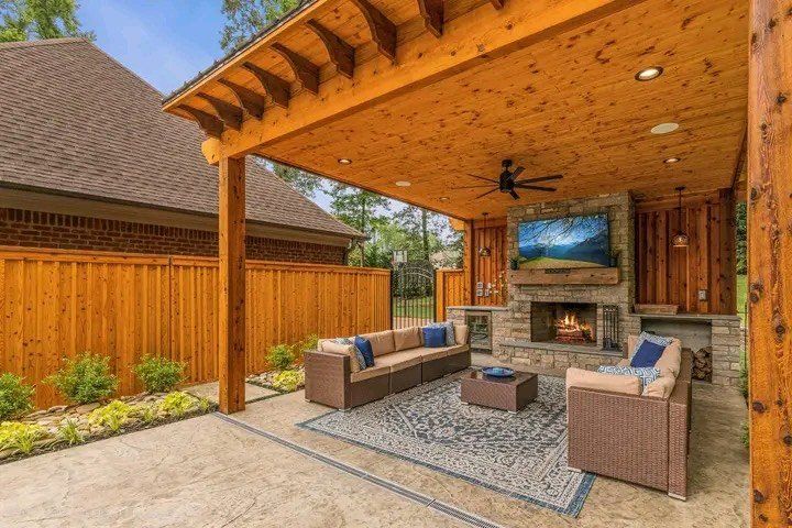 A covered patio with a fireplace and a flat screen tv.