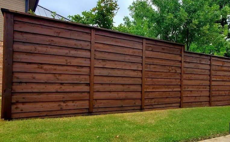 A large wooden fence is sitting on top of a lush green lawn.