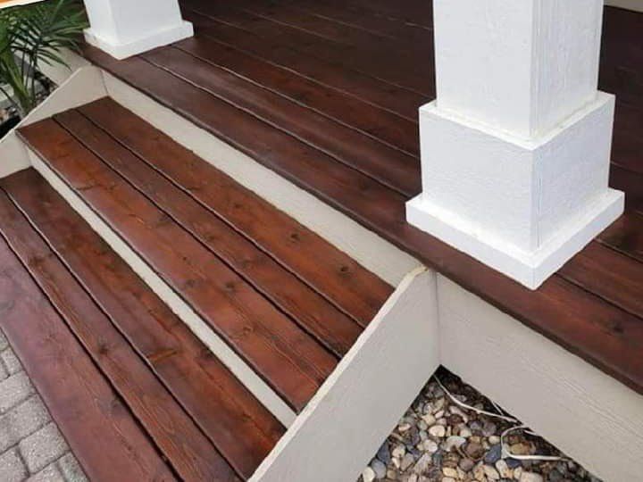 A wooden deck with white pillars and steps