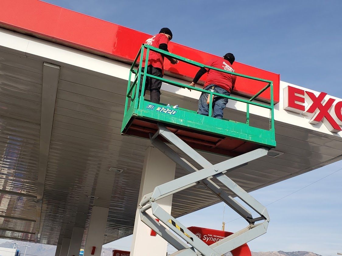 Two trucks are parked in a garage next to an american flag.