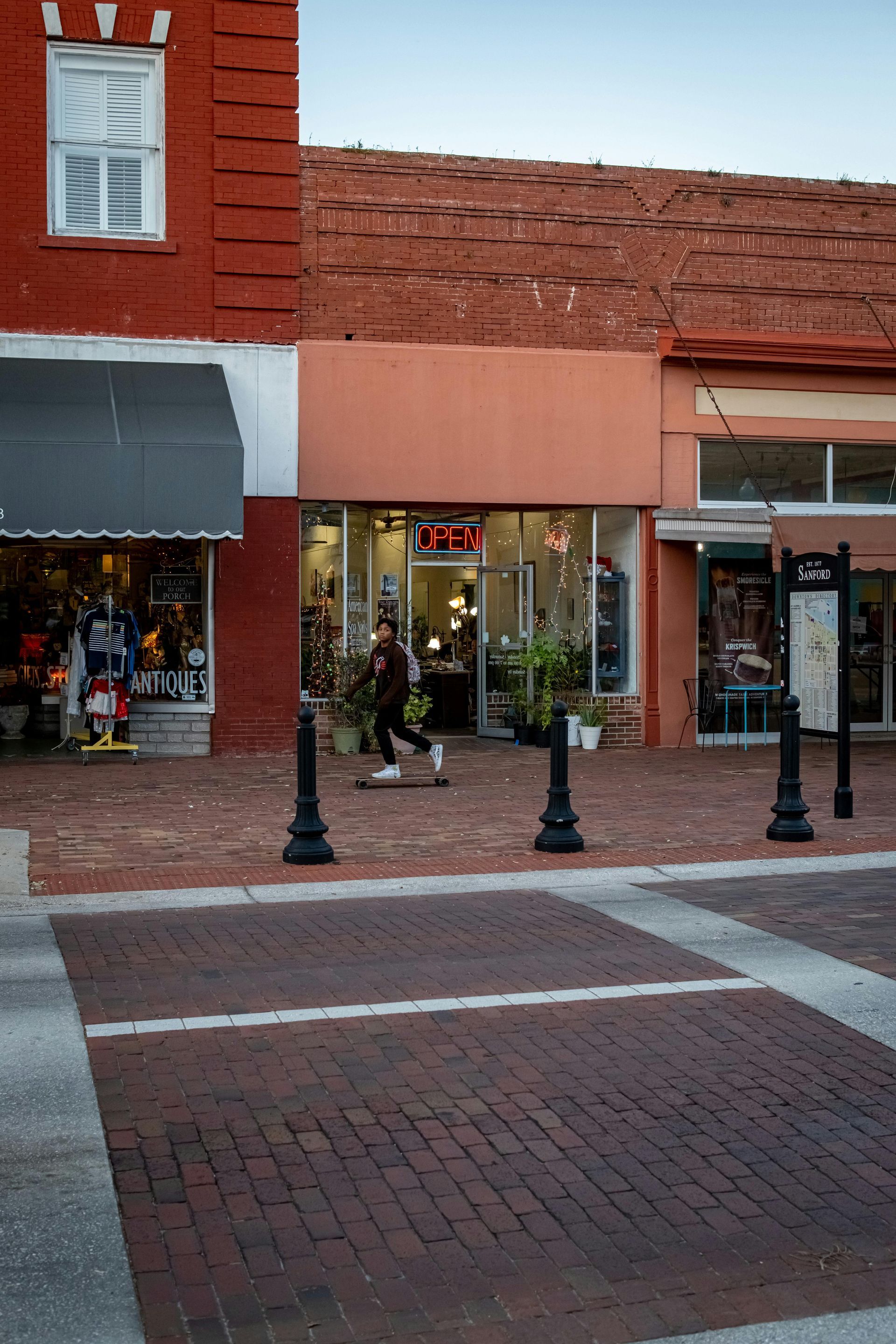White house with red trim and a picket fence, surrounded by fall foliage.