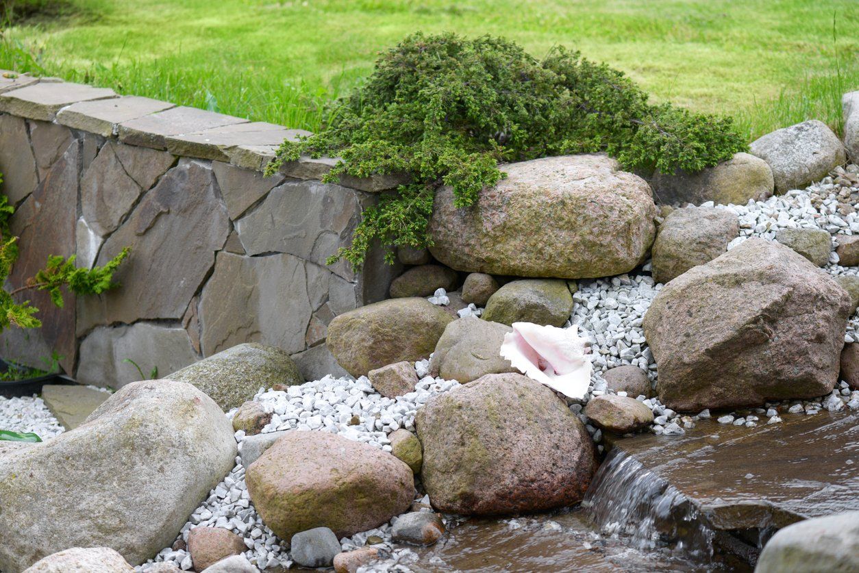 Granite Boulders in yard by retaining wall and waterfalll