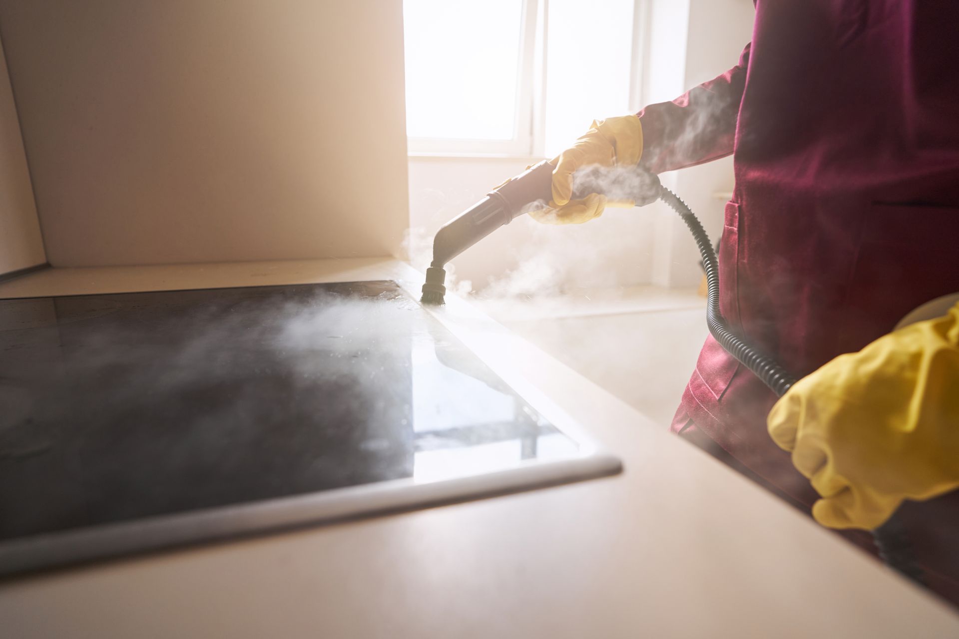 Person mopping a sunlit floor with a spray of cleaner near a doormat