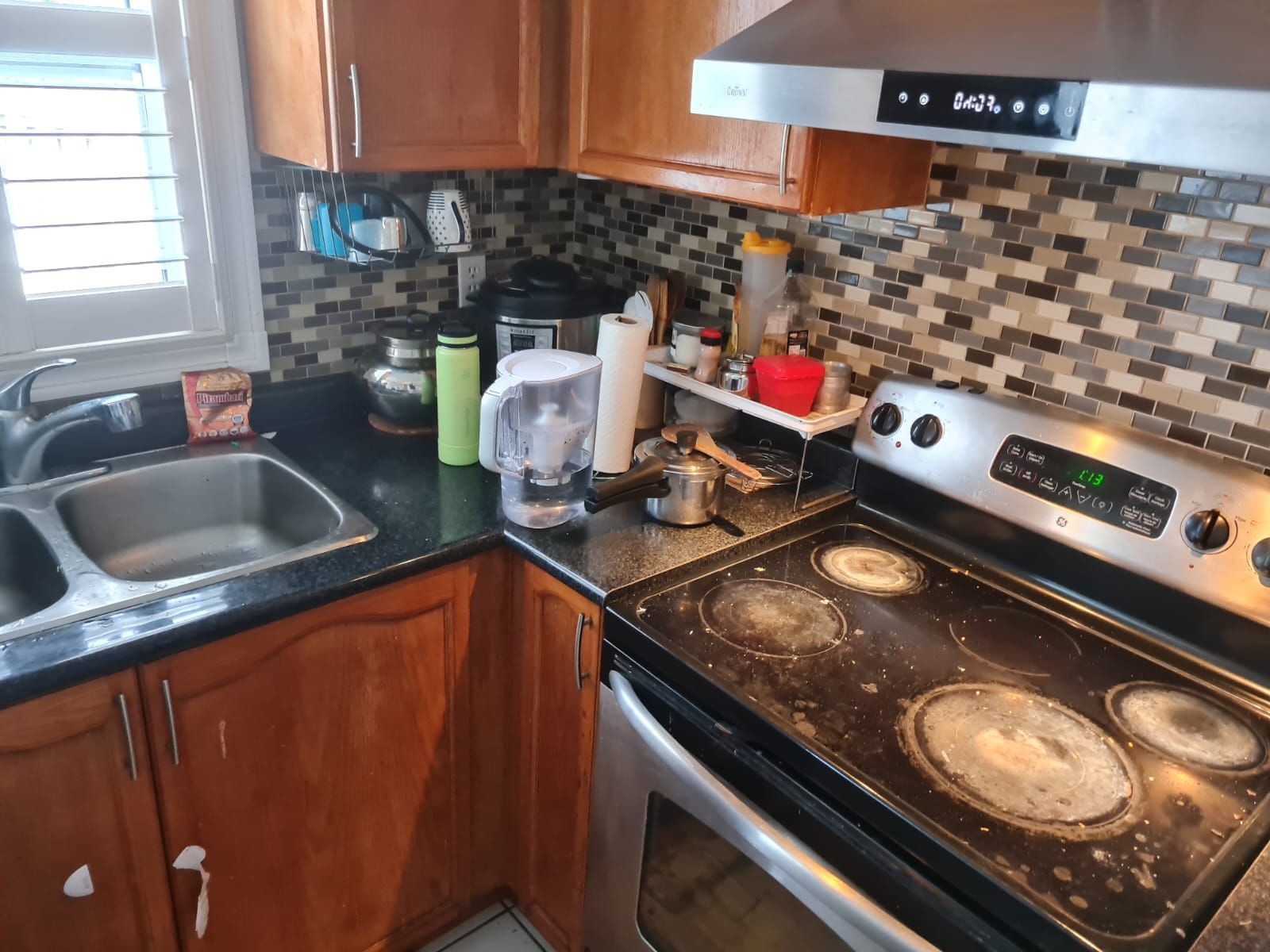 Kitchen with stainless steel stove, dark countertops, brown cabinets, and a tile backsplash.