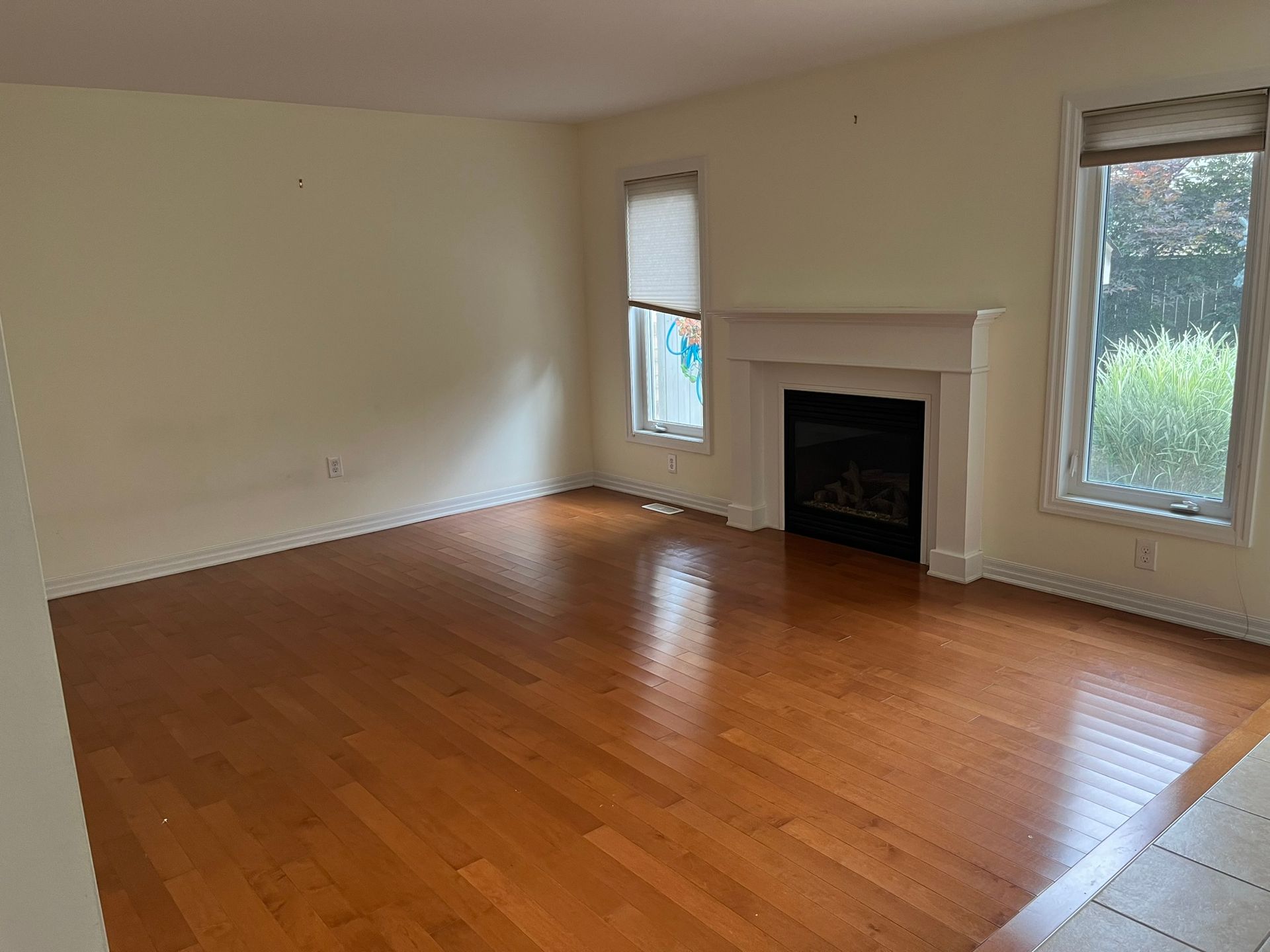 An empty living room with hardwood floors and a fireplace.