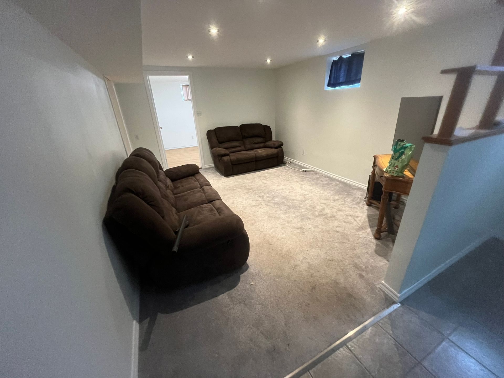 A living room with a brown couch and a desk.