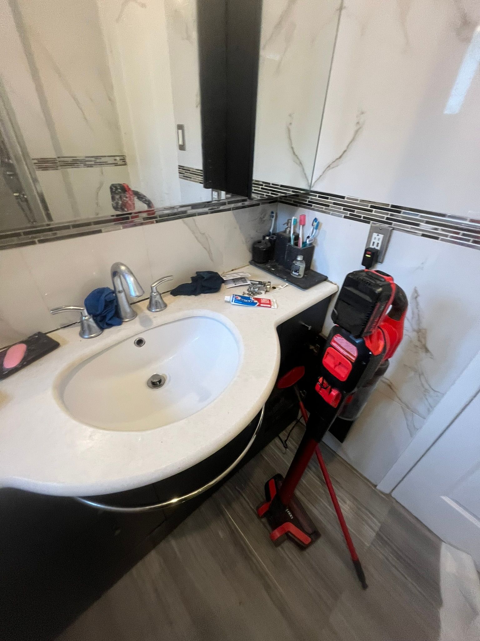 A bathroom with a sink , mirror and vacuum cleaner.