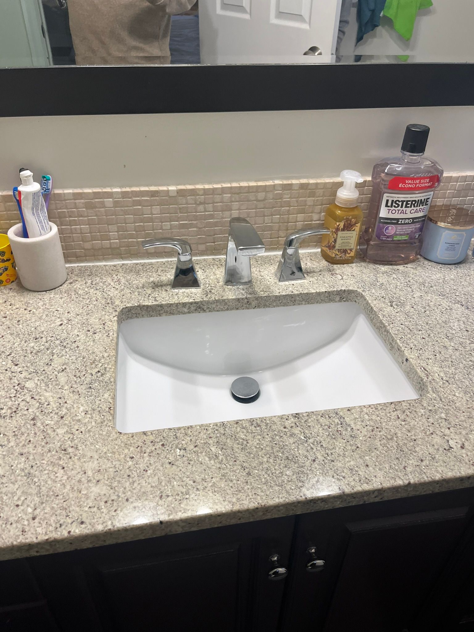 A bathroom sink with a bottle of mouthwash on the counter.