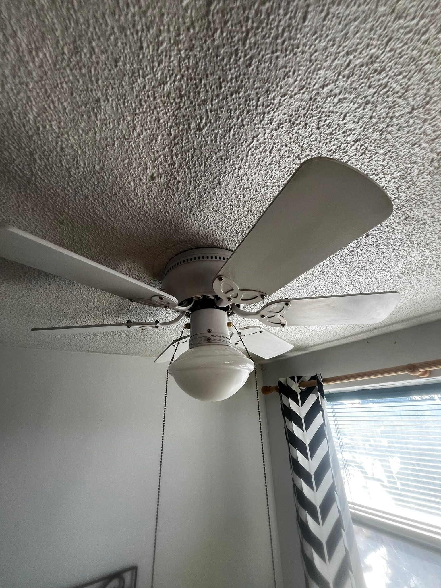 A white ceiling fan is hanging from the ceiling of a room.