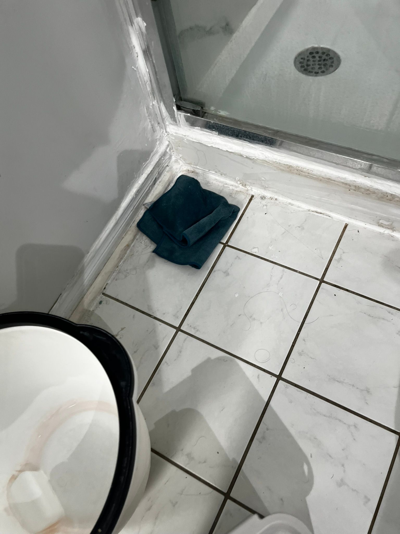 A towel is laying on the floor of a bathroom next to a toilet.