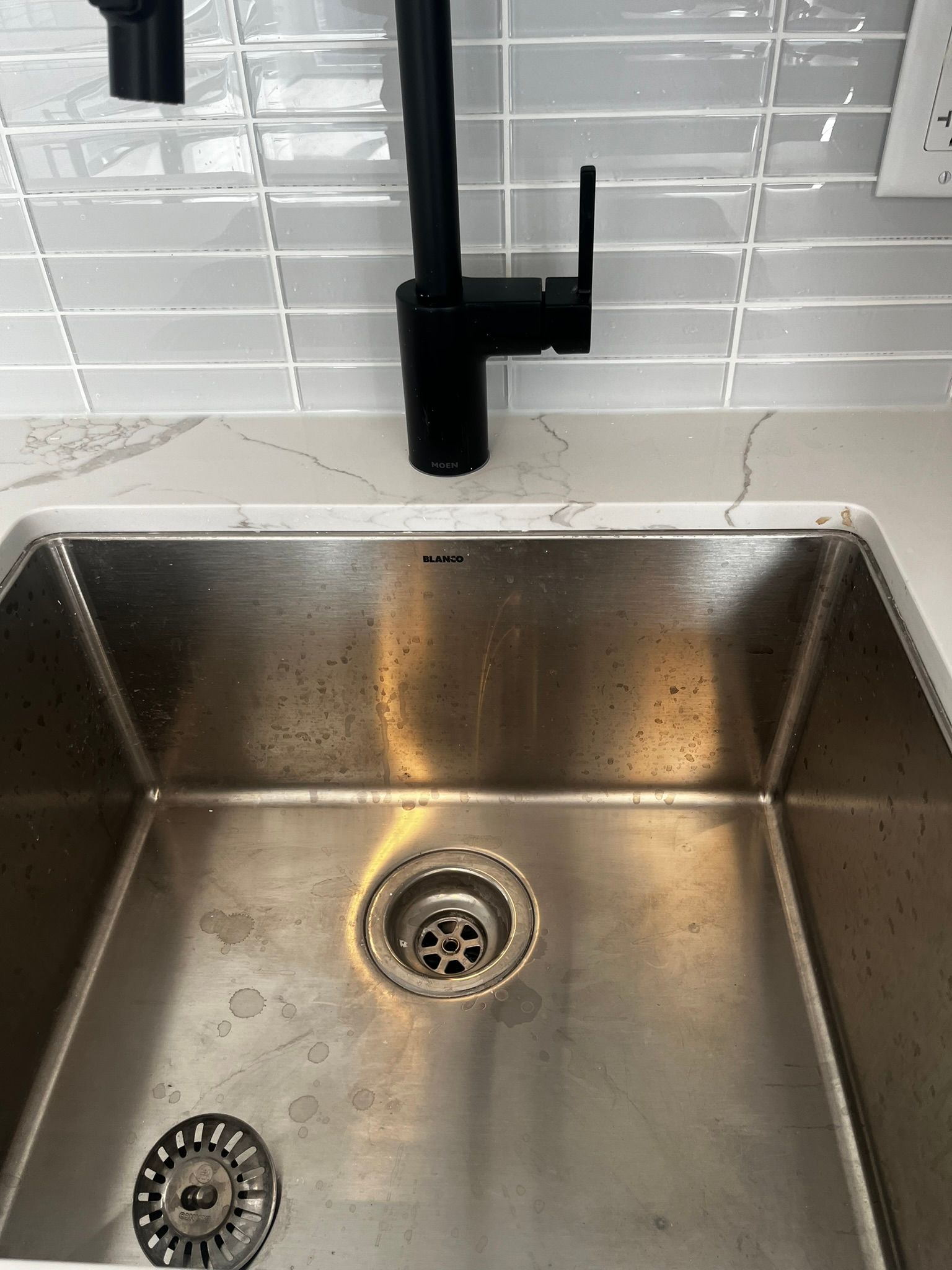 A stainless steel kitchen sink with a black faucet
