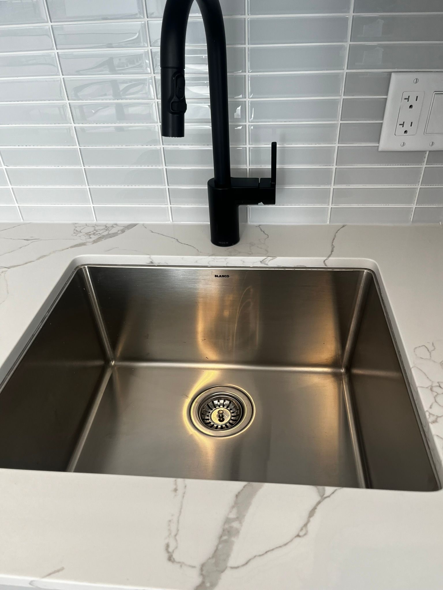 A stainless steel kitchen sink with a black faucet