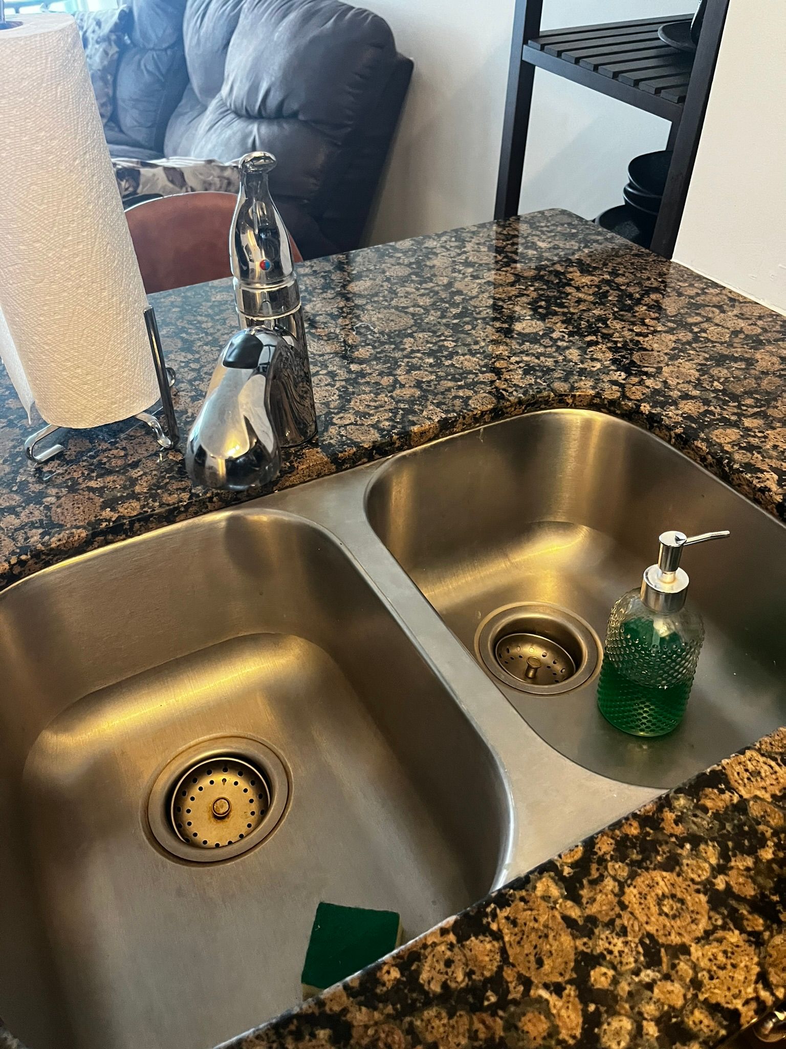 A kitchen sink with two sinks and a soap dispenser on the counter.