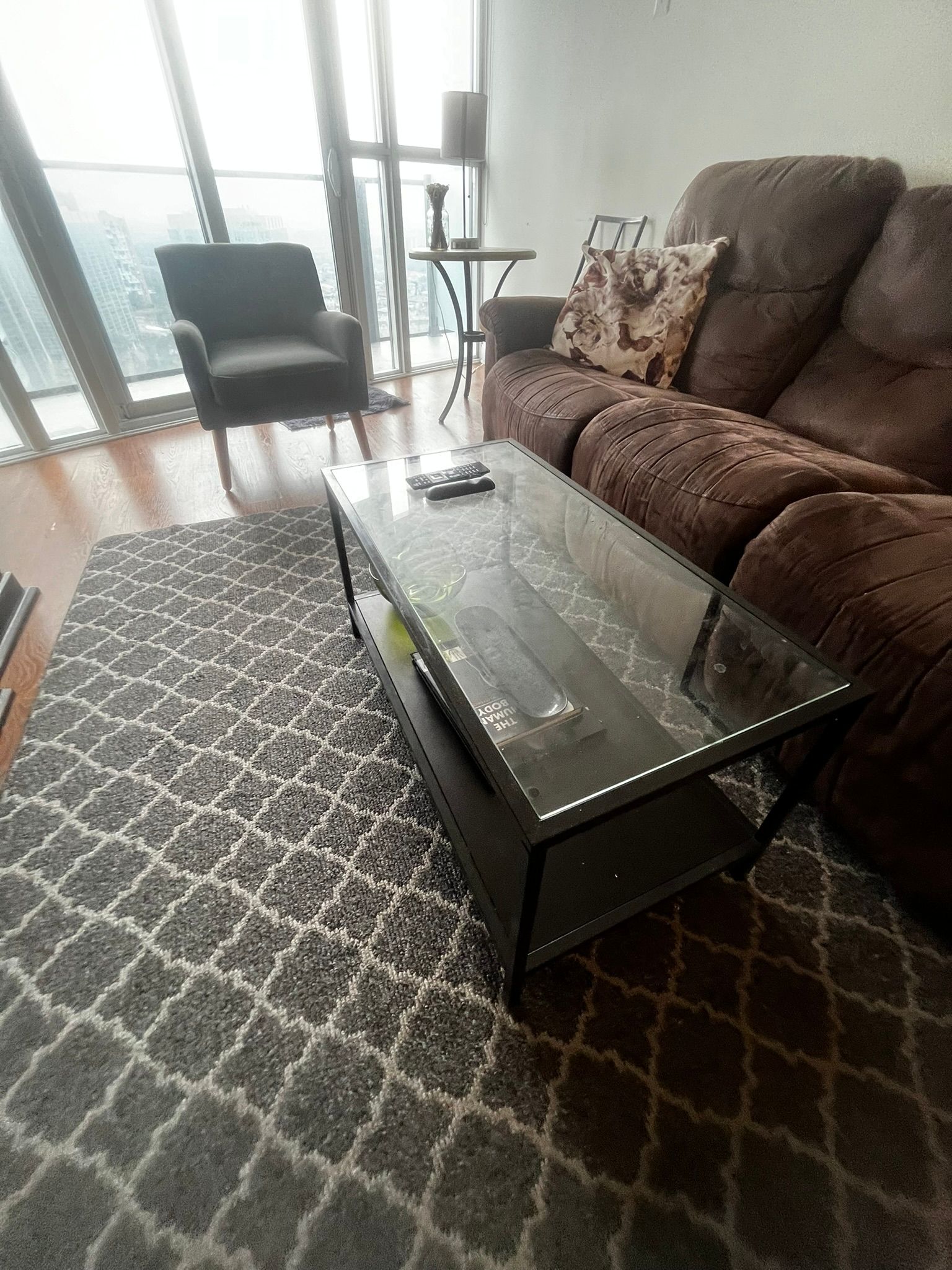 A living room with a couch , chair , coffee table and rug.