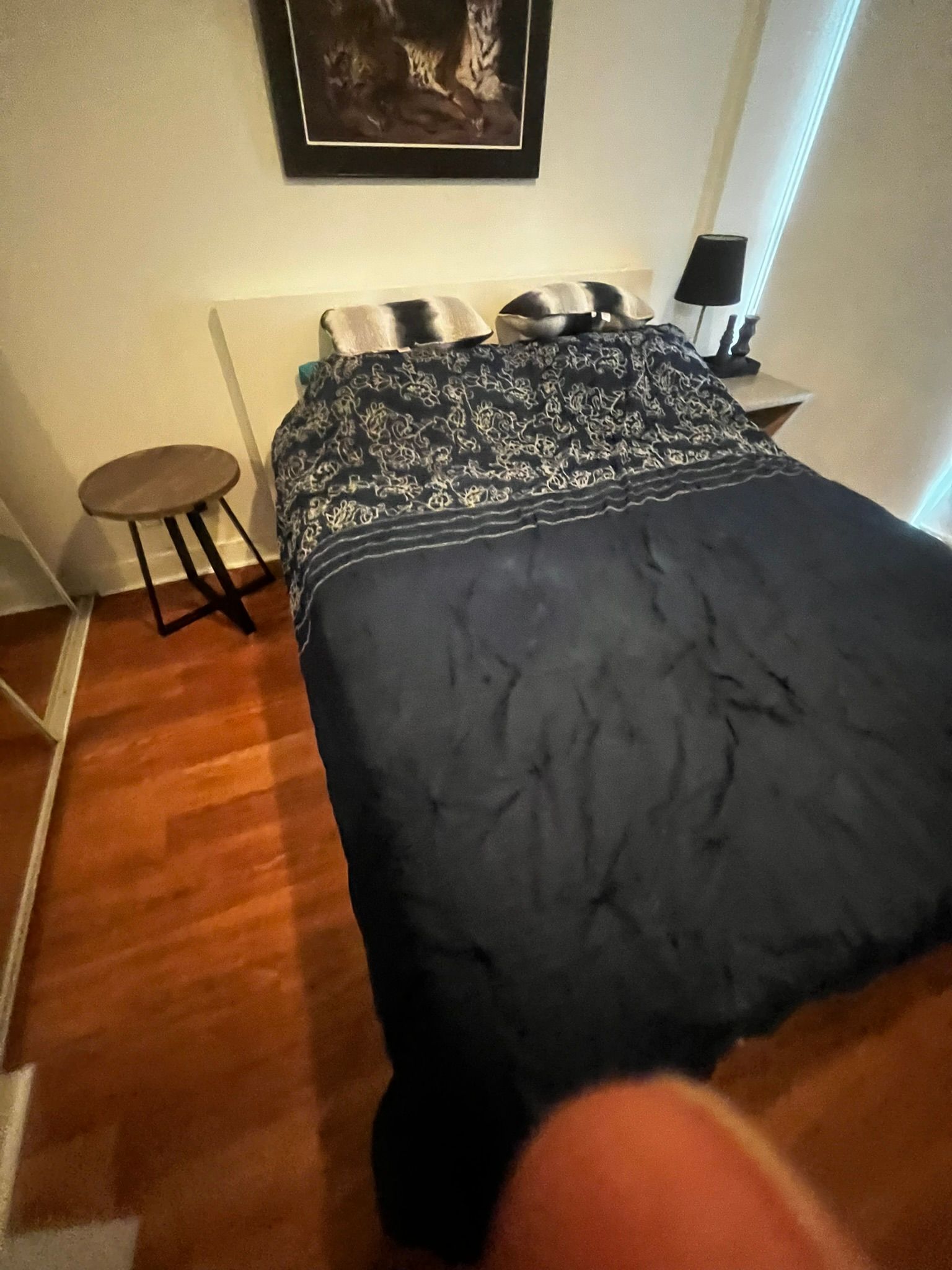 A bed in a bedroom with a picture on the wall above it