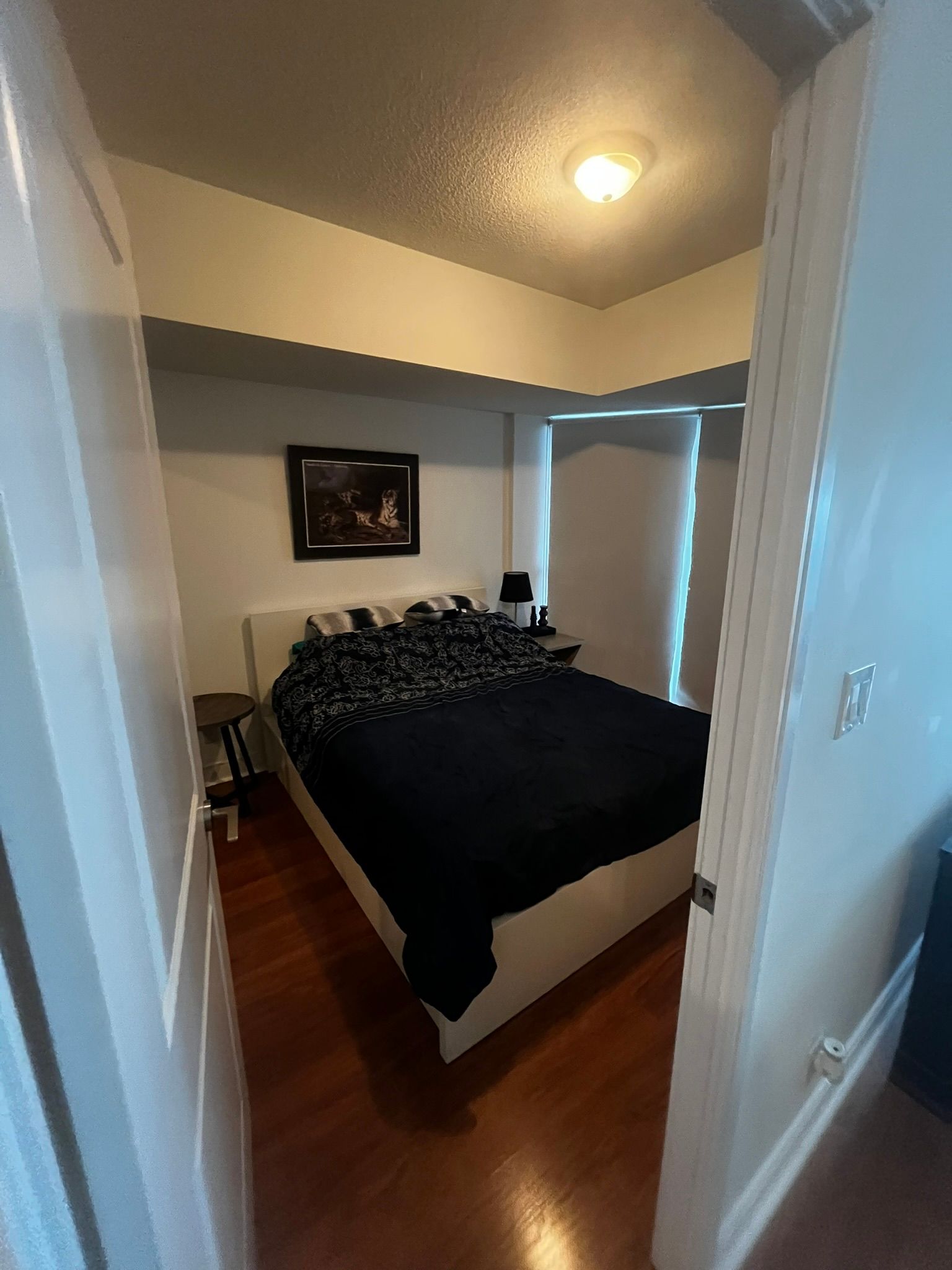 A bedroom with a bed and a picture on the wall.