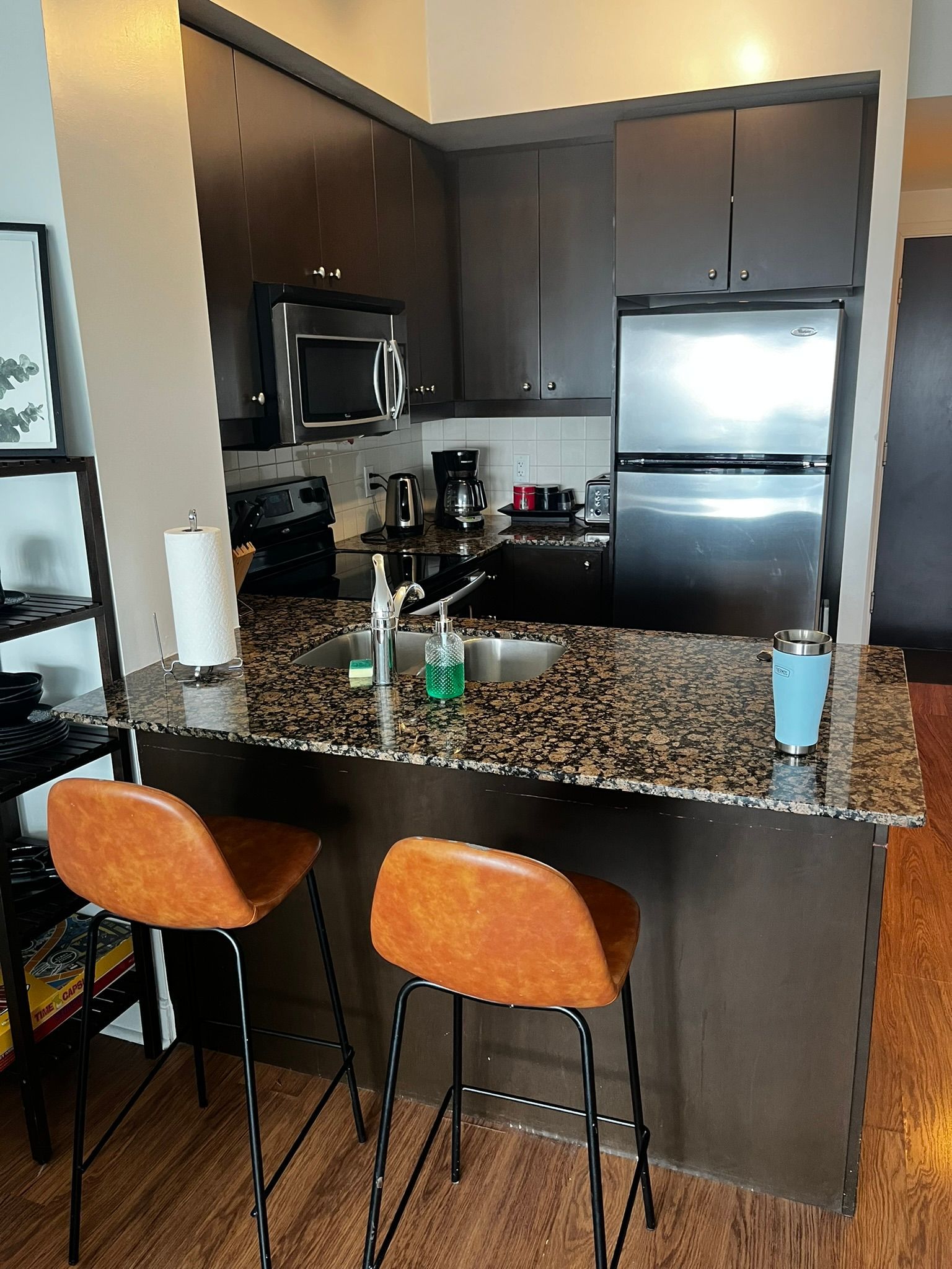 A kitchen with a granite counter top and two bar stools