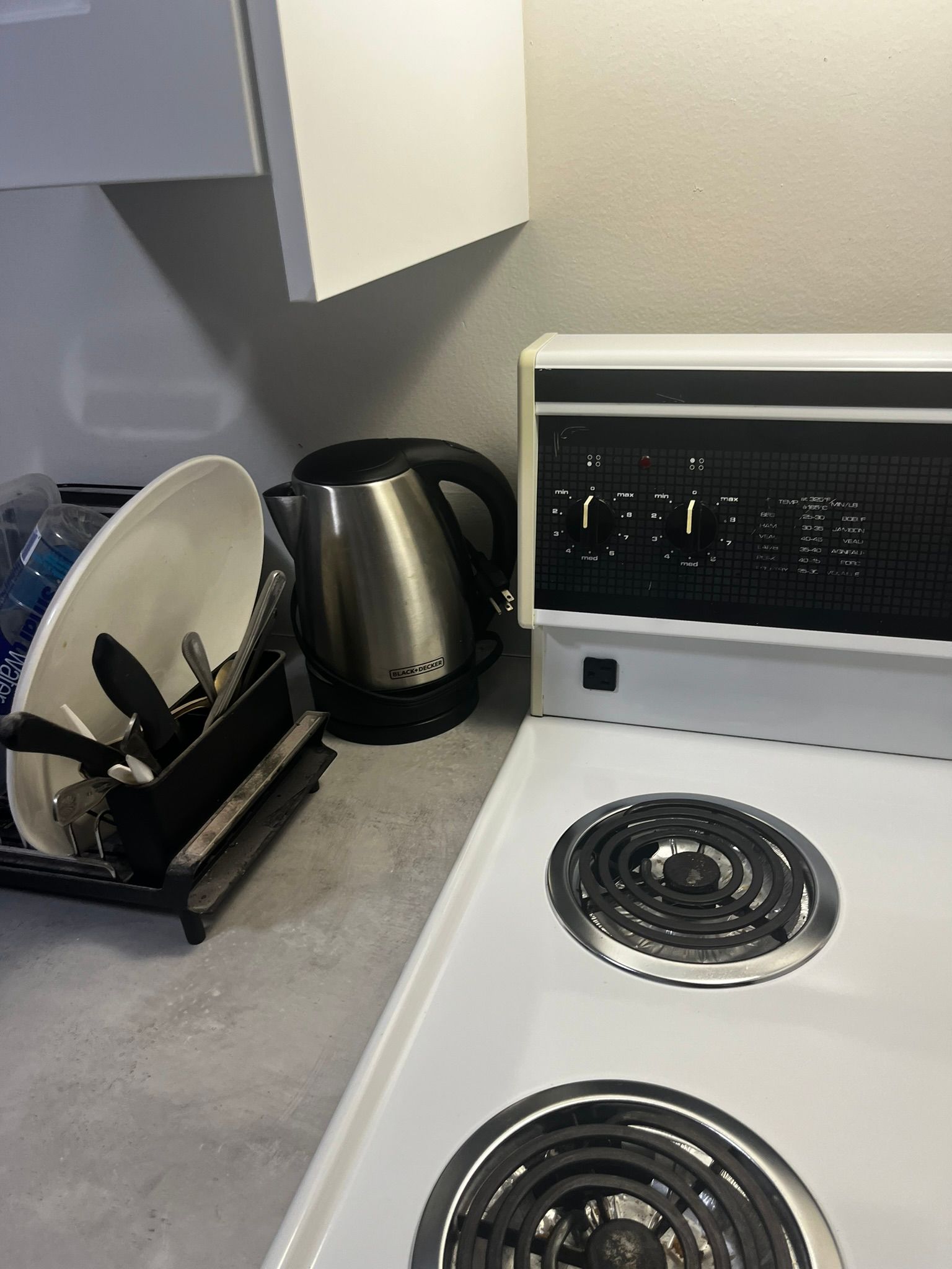 A kitchen with a stove , microwave , and dish rack.