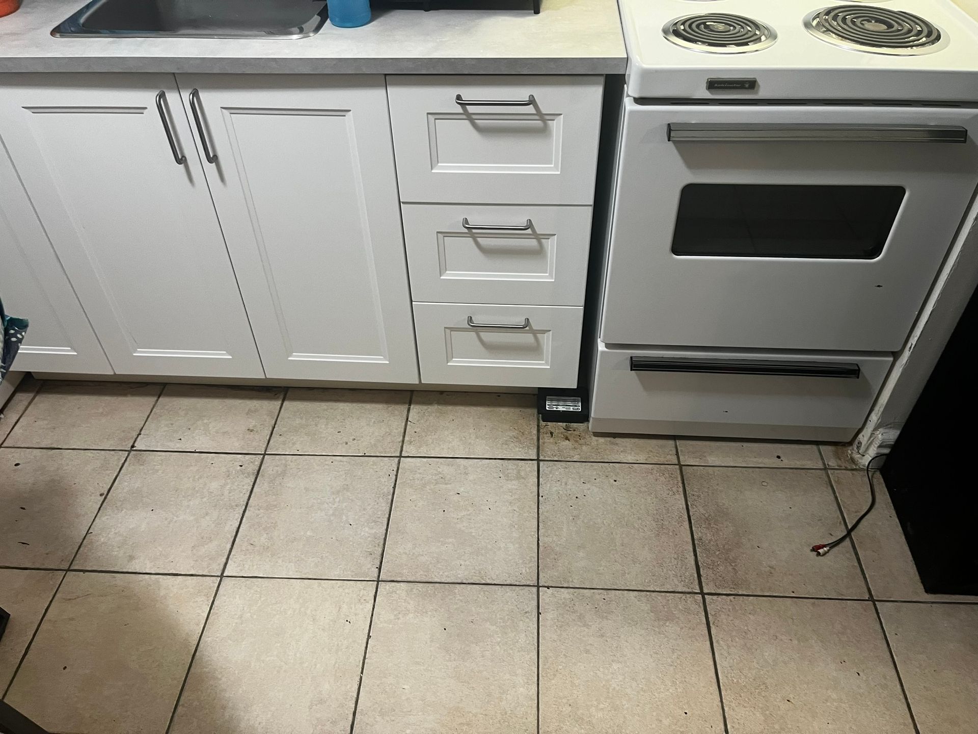 A kitchen with white cabinets , a stove and a sink