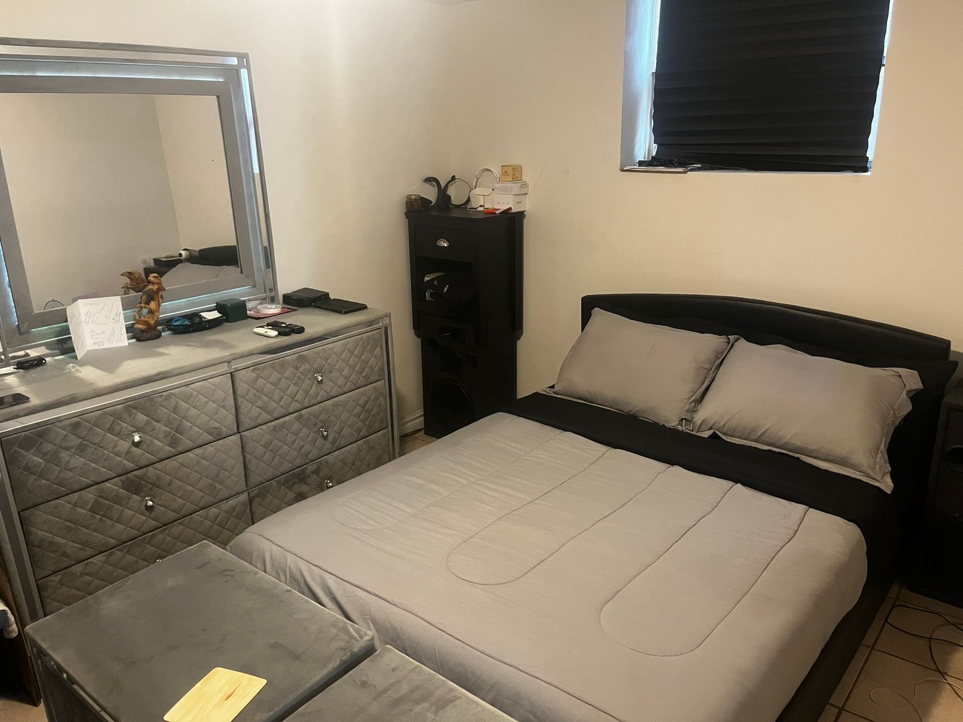 A bedroom with a bed , dresser , mirror and window.