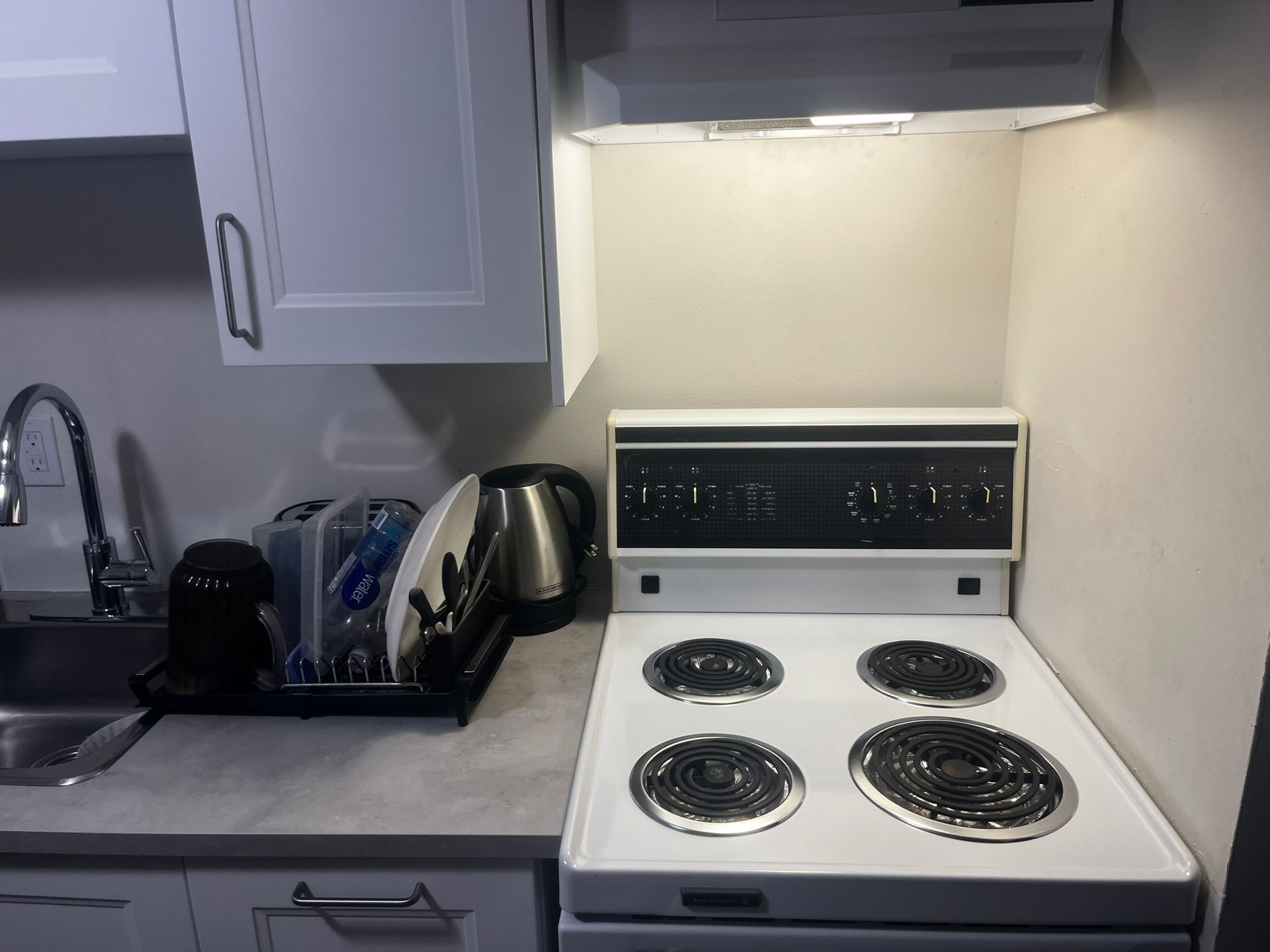 A kitchen with a white stove top oven and a sink.