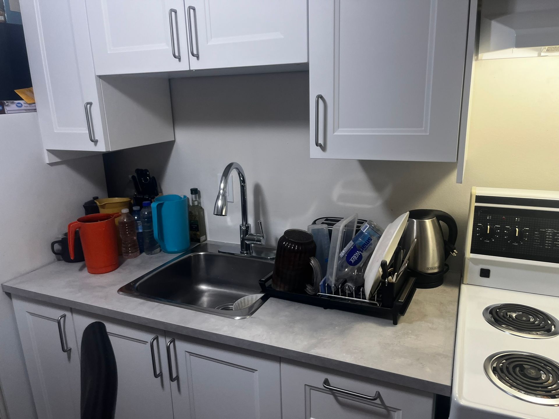 A kitchen with white cabinets and a sink and stove