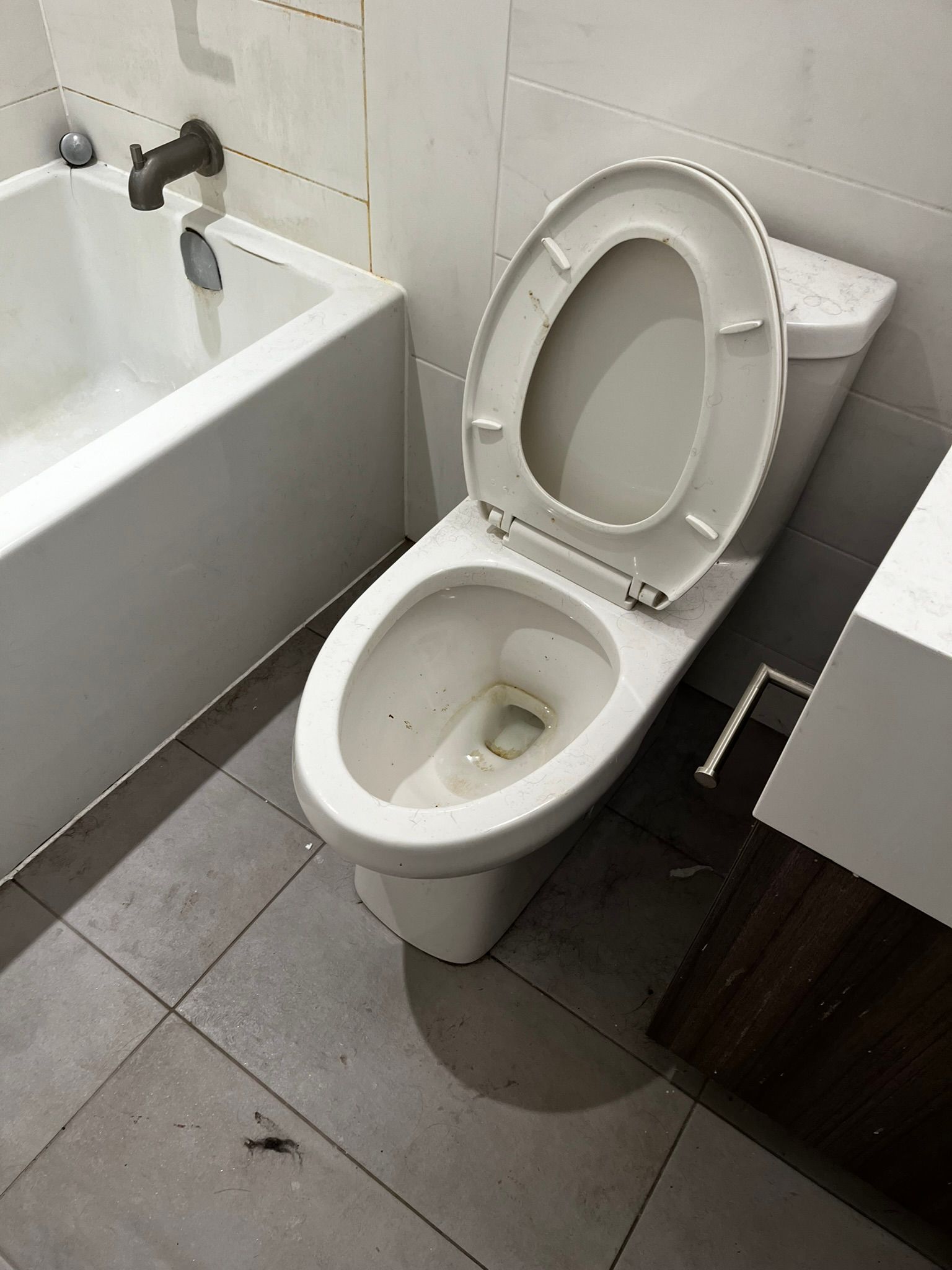 A toilet in a bathroom next to a bathtub