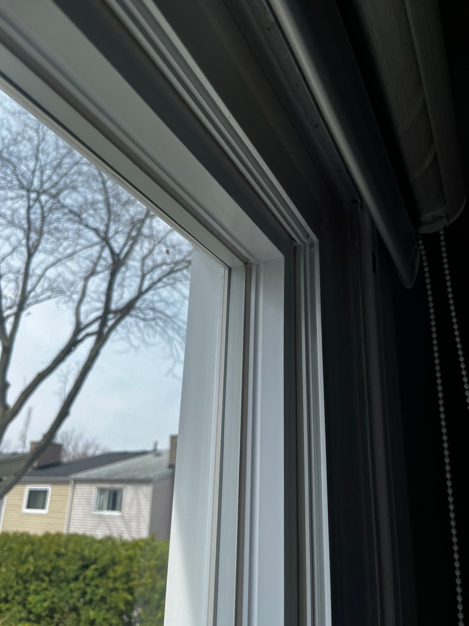 A close up of a window with a view of a house and trees.